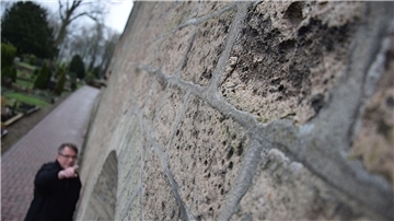 Mann zeigt auf Schäden an einer Mauer