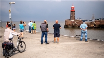 Schaulustige versammeln sich, um beim Abbau des Molenturms zuzusehen. Das Drama um den kleinen Leuchtturm geht den Menschen nahe - auch im Internet.