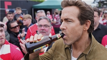 Schauspieler Ryan Reynolds lässt sich vor dem Spiel seines Clubs AFC Wrexham ein Bier schmecken.