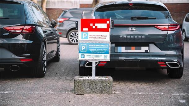 Parkende Autos und ein Hinweisschild auf einen Kundenparkplatz