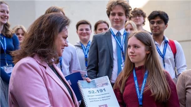 Schülerin Amelie überreicht die Unterschriftensammlung zur Abschaffung von Exen. Die Politikerin Ute EIling-Hütig soll sich nun damit befassen.