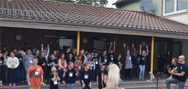 Schülerinnen und Schüler der Grundschule St. Willehad begrüßten mit fröhlichem Gesang, unterstützt von Lehrkräften, die Besucherinnen und Besucher des Sommerfestes.
