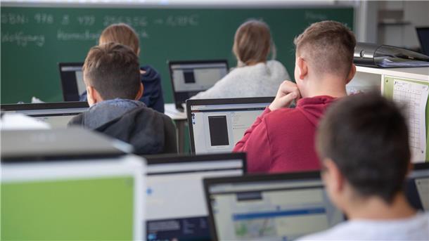 Schülerinnen und Schüler nehmen im Klassenzimmer einer 9. Klasse am Unterricht mit Hilfe von Laptops und Tablets teil.