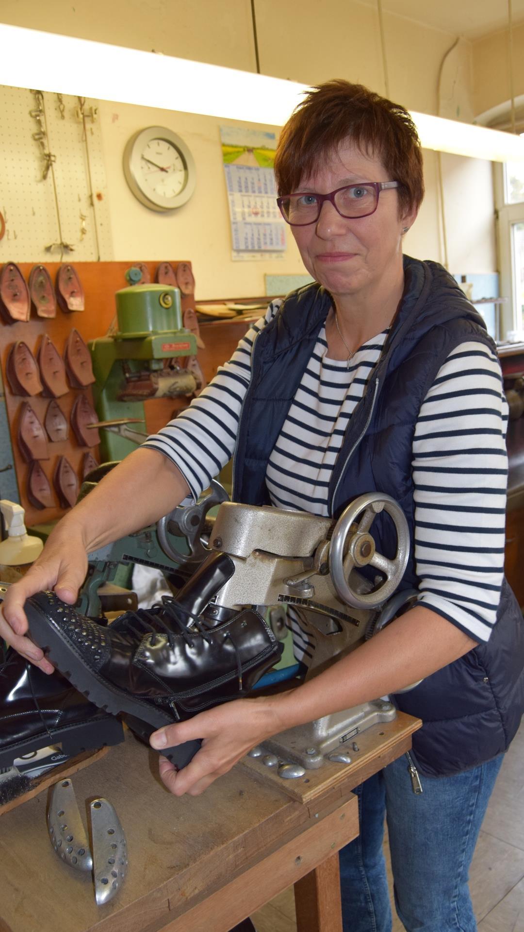 Eine Frau steht mit einem Stiefel in einer Schuhmacherwerkstatt