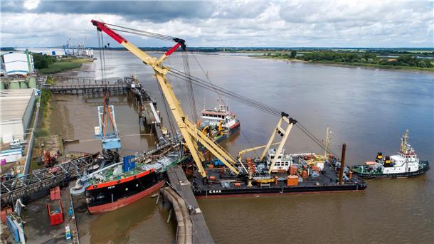 Schwimmkräne heben den havarierten Schiffsbelader im Braker Hafen.