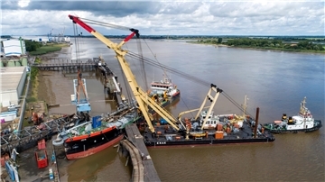Schwimmkräne heben den havarierten Schiffsbelader im Braker Hafen.