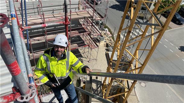 Mann steigt auf Treppe von Baugerüst nach oben.
