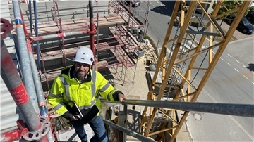 Mann steigt auf Treppe von Baugerüst nach oben.