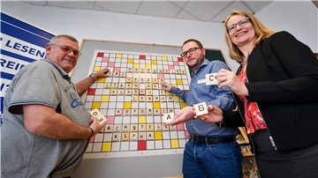Drei Menschen spielen Scrabble in groß.