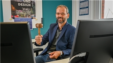 Ein Mann zeigt einen Hammer in die Kamera. 