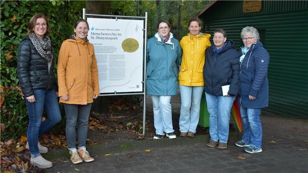 Sittensen präsentiert: Interaktiver Park der Menschenrechte Sechs Frauen stehen links und rechts neben einer großen Tafel an einem Parkzugang.