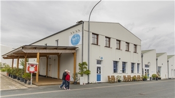 Eine alte Industriehalle, jetzt ein Café: Davor laufen Spaziergänger.