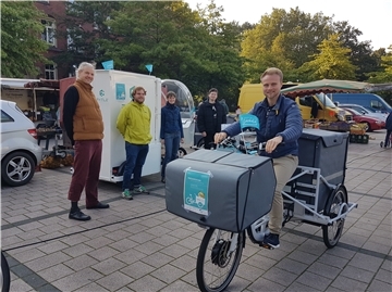 Sich Einkäufe gratis nach Hause liefern zu lassen, ist ein Service von „Lehe liefert“. Das Team von "Lehe liefert" stellte die Idee auf dem Wochenmarkt in Lehe vor. Auf dem Fahrrad Lars Wöltjen, im Hintergrund von links: Felix Liebig, Richard Schulte, Uta Kühne, Mattes Leibenath.