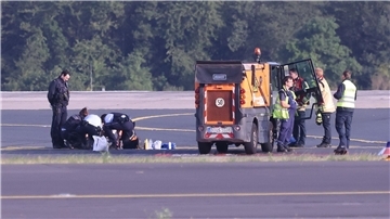 Sicherheitspersonal und Polizisten versuchen am Düsseldofer Flughafen, Aktivisten vom Asphalt auf dem Rollfeld zu lösen.