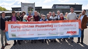 Viele Menschen halten ein Banner.