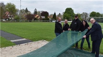 Sie nehmen die Plane der erneuerten Sprunggrube auf dem Seefelder Sportplatz in Augenschein (von links): Ratsmitglied Jürgen Neels aus Seefeld, Bauamtsmitarbeiter Robby Müller, Jürgen Böning (Vorsitzender der Dorfgemeinschaft), Katja Eilers (stellvertretende Vorsitzende der Dorfgemeinschaft) und Bürgermeister Harald Stindt.