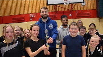 Kinder und zwei Erwachsene mit Siegerpokal