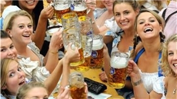 Frauen im Dirndl stoßen mit Maßkrügen an