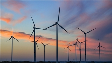Farbenprächtig leuchten Wolken am Morgenhimmel kurz vor Sonnenaufgang über einem Windpark