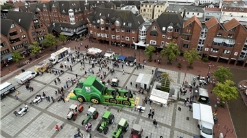 Eine Luftaufnahme zeigt den Nordenhamer Marktplatz mit dutzenden Menschen, Traktoren und Ständen. 