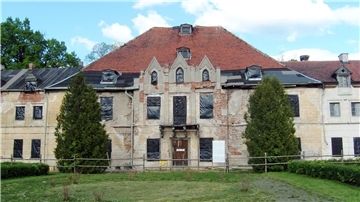 Ein marodes Schloss dessen Fensteröffnungen mit schwarzer Folie verschlossen sind 