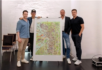Vier Männer stehen um das Wimmelbild herum