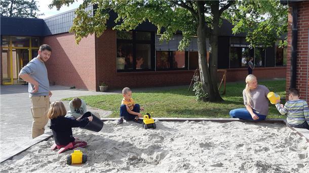 Kinder und Erwachsene an und in einem Sandkasten