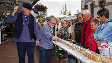 Der Matjesorden mit Sönke Allers (links) und Gerd Blancke (2. von links) verkauft ein riesiges Fischbrötchen für den guten Zweck.