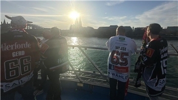 Menschen stehen in Köln auf einem Schiff