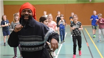 Spaß und Bewegung in der Turnhalle: Tanzlehrer Julius Nartey zeigt den Mädchen und Jungen der Klasse 4a, wie es geht.