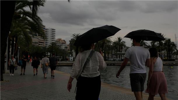 Rekord-Niederschläge: Starke Überschwemmungen auf Mallorca Spaziergänger mit Regenschirmen sind an der Strandpromenade von Palma unterwegs.