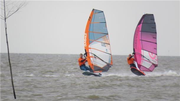 Zwei Windsurfer auf dem Wasser.