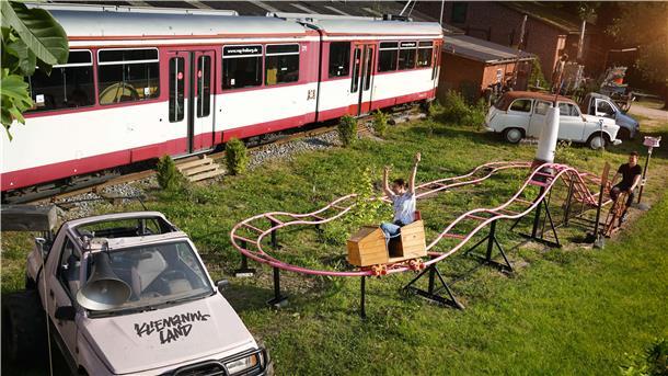 Eine stillgelegte Straßenbahn, eine Achterbahn und verschiedene Autos im Kliemannsland in Rüspel.