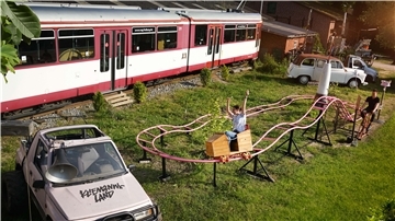 Eine stillgelegte Straßenbahn, eine Achterbahn und verschiedene Autos im Kliemannsland in Rüspel.