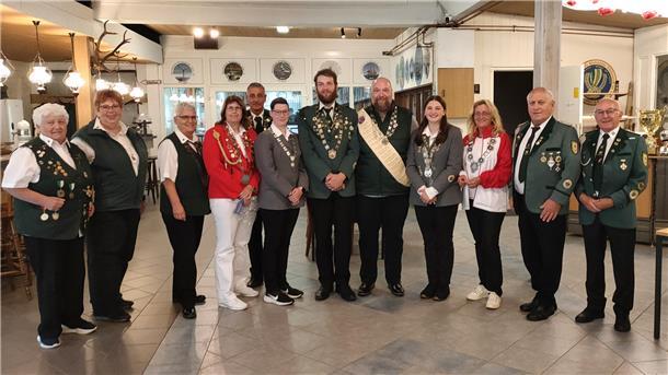 Sportschützen posieren in einem Vereinsheim in ihrer Tracht.