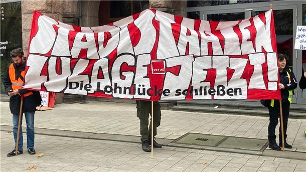 Wegen „Stadtstaatenstreiks“ drohen Einschränkungen „Stadtstaaten - Zulage jetzt! - Die Lohnlücke schließen“ steht auf einem Plakat, das Demonstrierende vor dem Gewerkschaftshaus halten.