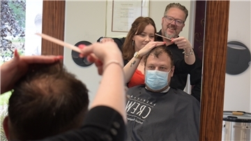Stefan Hartmann (hinten), Inhaber des Friseursalons „Haarscharf“ in Hagen, ist zufrieden mit der Arbeit seiner Auszubildenden Leeann Köster, die sich gerade um den Haarschnitt von Nick Mehrtens kümmert.