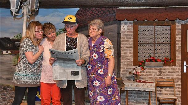 Steffi Seemann (als Schwanette), Jutta Misfeld (als ihre Mutter), Rosemarie Hermann (als Postpotin Meta Knudsen) und Christa Cords (als Berta Brinkmann) lesen auf dem Misselwardener Dorfplatz die neuesten Nachrichten in der Nordsee-Zeitung über den Lottogewinn.