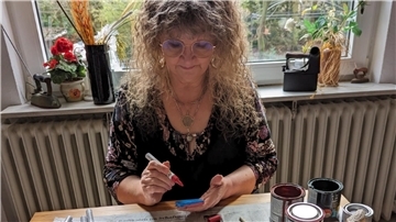 Frau malt Steine an