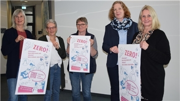 Mehrere Damen stehen zusammen. Sie halten Poster in der Hand, die auf die bevorstehende Ausstellung "Wenn schwanger, dann Zero!" ab dem 22. April hinweisen.