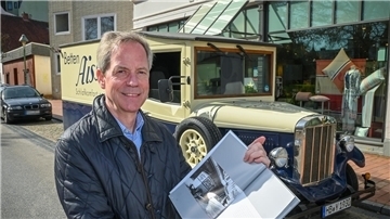 Ein Mann steht vor einem Oldtimer.