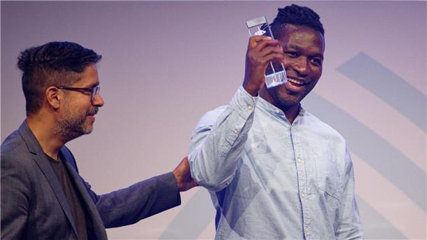 Steve Hiobi (r) und Laudator Hasnain Kazim stehen bei der Verleihung des Grimme Online Award 2023 mit dem Preis für „Dein Bruder Steve“ in der Kategorie „Information“ auf der Bühne.
