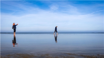 Strandspaziergänger sind an der Ostsee am Wohlenberger Wieck unterwegs.