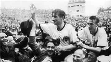 Stürmer und Kapitän Fritz Walter (Mitte) und sein Lauterer Teamgefährte Horst Eckel (rechts) werden nach dem Triumph im Fußball-WM-Finale im Berner Wankdorfstadion 1954 von begeisterten Anhängern vom Spielfeld getragen.