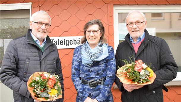 Zwei Männer mit Blumensträußen und eine Frau