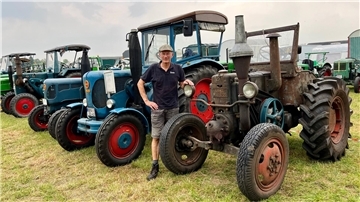 Ein Mann steht an einem 84 Jahre alten Traktor, dahinter sind weitere Traktoren zu sehen.