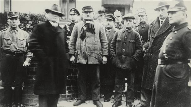 Vor dem Haus des jüdischen Viehhändlers Erich Neugarten an der Zevener Gartenstraße haben der Führer des Zevener SA-Sturms Wilhelm Schnasse (links) und seine Männer Erich Neugarten (Zweiter von rechts), Hermann Samson (Vierter von rechts), Bernard Blumert (Sechster von rechts) vermutlich Kurt Deichmann (hinter Blumert), Alfred Rosenthal (Vierter von links) und vermutlich den jüdischen Tuchhändler Gustav Kleinschmidt (Zweiter von links) am 10. November 1938 vor dem Abtransport zur Gestapo versamm