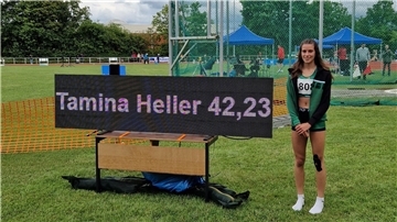 Tamina Heller steht auf dem Sportplatz neben der Anzeigetafel, die ihre Rekordzeit von 42,23 Sekunden über 300 Meter Hürden zeigt.