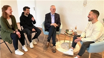 Vier Erwachsene sitzen im Halbkreis und unterhalten sich