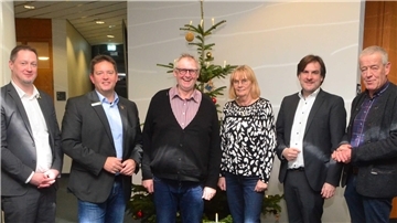 Fünf Männer und eine Frau vor einem Weihnachtsbaum